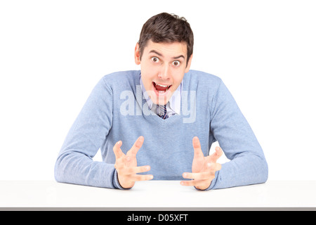 Angry young man sitting and gesturing with hands isolated on white background Stock Photo