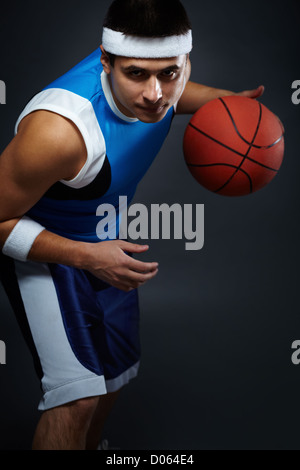Portrait of handsome guy in sportswear playing basket ball