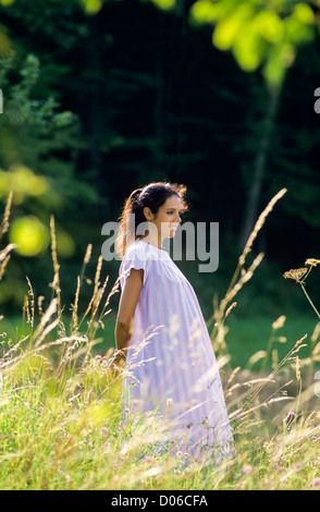 Pregnant woman standing in meadow Stock Photo