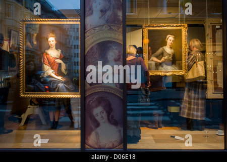 Art lovers are seen through a window while attending a private exhibition preview of a series at Phillip Mould, a dealer of paintings in London. Philip Mould & Company are a leading specialist dealer in British art and Old Masters. Our gallery is located in Dover Street at the centre of London’s art market. They have a large selection of fine paintings for sale, from Tudor and Jacobean panel pictures to eighteenth century landscapes, as well as works by Old Masters such as Titian and Van Dyck, and antique portrait miniatures. Stock Photo