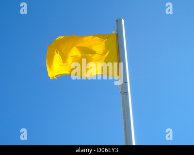 A yellow flag on the blue sky blowing in the wind Stock Photo