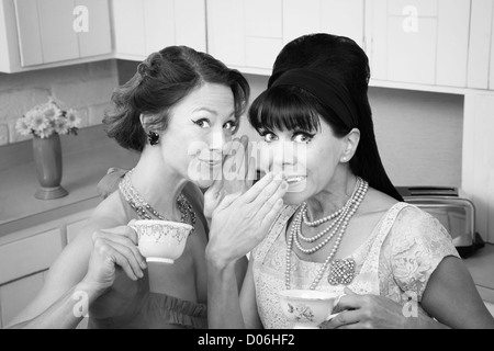 Middle-aged retro styled Caucasian woman whispers secret to her friend Stock Photo