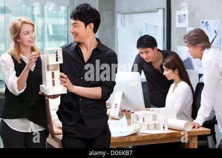 Architects holding architectural model with the team in background Stock Photo
