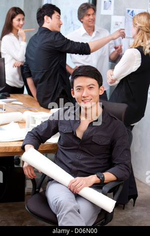 Architect holding blueprint with his team in background Stock Photo
