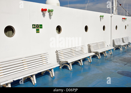 Row of benches and portholes on ship deck painted with white and blue colors. Stock Photo