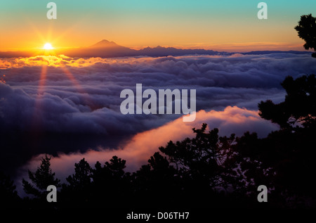 The sun rises behind Mount Baker as seen from the top of Mount Constitution on Orcas Island Stock Photo