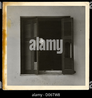 Vintage photograph of masked figure by the broken windows of abandoned house. Stock Photo