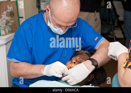 Male volunteer dentist provides dental services for black woman through Mission Smiles mobile dental clinic in Tampa, FL Stock Photo