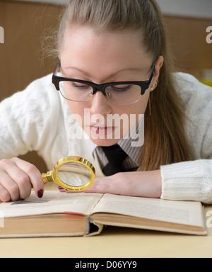 woman reading a book with a magnifying glass Stock Photo