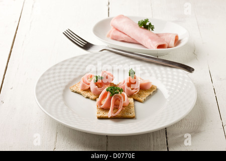 photo of cracker appetizer with  ham and parsley on white wooden table Stock Photo