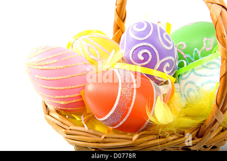 Cane basket with colorful easter eggs over white background Stock Photo