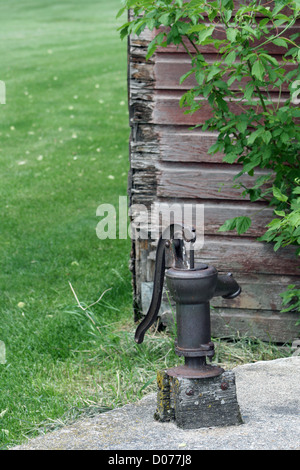 An antique cast iron water pump on a concrete cistern in spring on a farmers yard in Altona, Manitoba, Canada Stock Photo