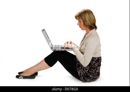 A young woman sitting on the floor and working on her laptop Stock Photo
