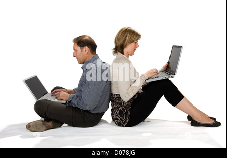 A couple sitting on the ground both at work on the laptop Stock Photo