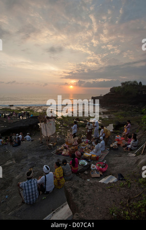 Balinese people offering presents to their gods,in Tanah Lot ,as the sun goes down . Stock Photo