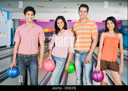 Two young couples holding bowling balls in a bowling alley Stock Photo