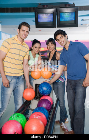 Two young couples holding bowling balls in a bowling alley Stock Photo