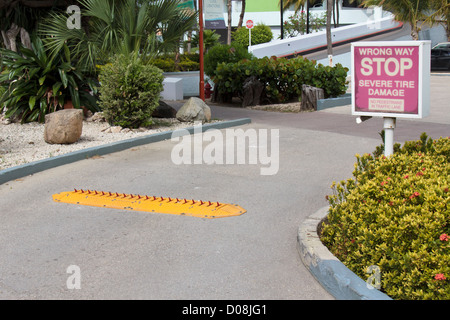 parking lot exit with traffic spikes and warning sign - stop severe tire damage Stock Photo