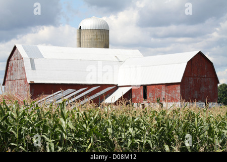 Solar Panels erected in an open field next to an old red barn Stock Photo