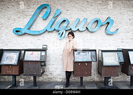 Girl posed in front of Liquor sign Stock Photo