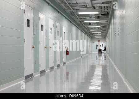 Hallway and prison cells Observation hatches in the doors. A Correctional Facility. A desk and table at the end. Stock Photo