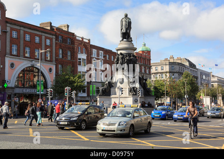 Busy street scene with city traffic passing Daniel O'Connell Monument on O'Connell Street, Dublin, Southern Ireland, Eire Stock Photo