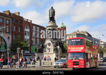 Red double decker Hop on Hop off city sightseeing tour bus passing Daniel O'Connell Monument on street. Dublin city Ireland Eire Stock Photo
