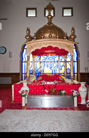 A Takhat Containing the Manji Sahib Covered In Red Silk Rumallas In a Darbar Sahib In A Sikh Temple Stock Photo