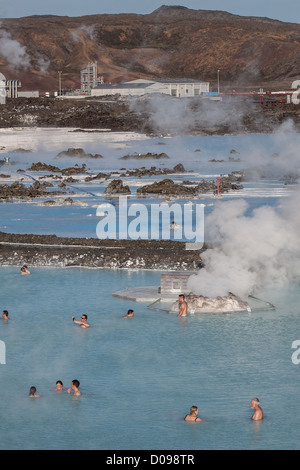 BATHERS ENJOYING HOT WATER BLUE LAGOON IN BACKGROUND SVARTSENGI GEOTHERMAL PLANT HOT SPRINGS SILICA MUD GRINDAVIK REYKJANES Stock Photo