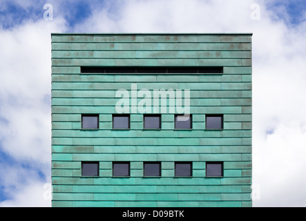 Square facade with copper strips against cloudy sky Stock Photo