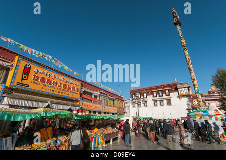 As Budhist pilgrims circle Jokhang Temple, tourist souvenir shops crowd Barkhor Square, Lhasa, Tibet, China Stock Photo