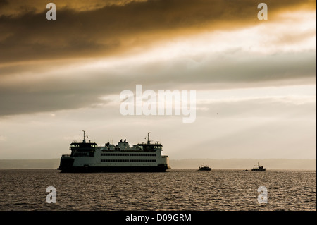 A Washington State Ferry leaves Port Townsend, Washington headed for Keystone during a dramatic sunrise in Puget Sound. Stock Photo