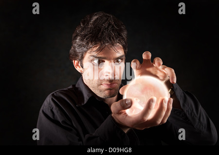 Male fortune-teller gazes over a crystal ball Stock Photo