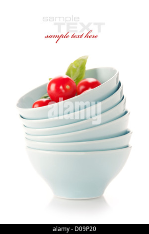 Stack of bowls and fresh tomatoes over white (with sample text) Stock Photo