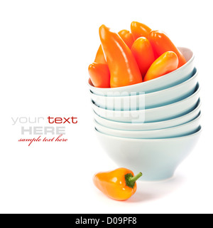 Stack of bowls and fresh orange peppers over white Stock Photo