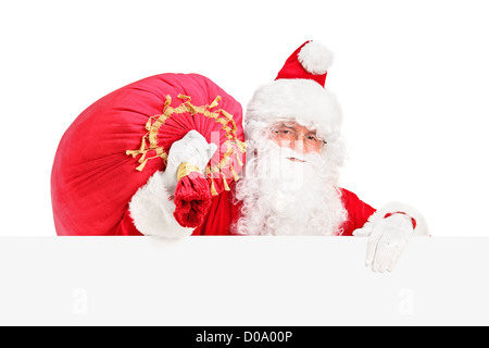 Santa Claus carrying a bag and posing behind a blank billboard isolated on white background Stock Photo