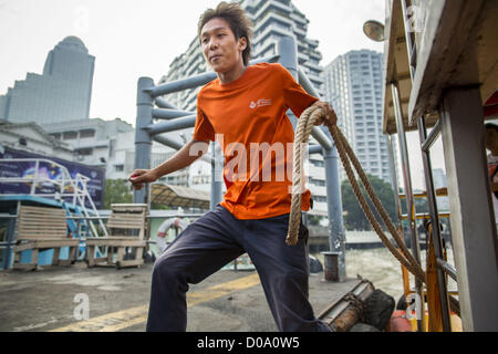 Nov. 21, 2012 - Bangkok, Thailand - A crewman jumps off a still moving Chao Phraya Express Boat to tie it to the pier so passengers can embark and disembark. The Chao Phraya Express boats run up and down the Chao Phraya River in Bangkok providing a sort of bus service for neighborhoods near the river. The boats are the fastest way to get from north to south in Bangkok. Thousands of people commute to work daily on the Chao Phraya Express Boats and fast boats that ply Khlong Saen Saeb. Boats are used to haul commodities through the city to deep water ports for export. (Credit Image: © Jack Kurtz Stock Photo