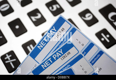 BRITISH PAYSLIPS SHOWING NET PAY AMOUNTS WITH CALCULATOR RE WAGES INCOMES SALARY SALARIES INTEREST RATES INFLATION SLIPS CASH UK Stock Photo