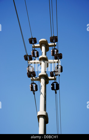 Transformers of an electrical post with powerlines against bright blue sky. Stock Photo