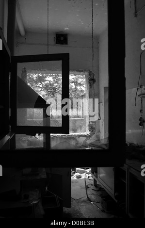 Broken window frames and reel tape on abandoned factory floor. Black and white. Stock Photo