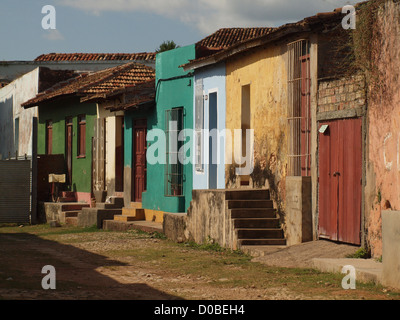 row of brightly painted houses with steps from cobbled street  in run-down area of Trinidad Cuba Stock Photo