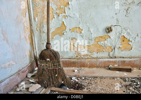 Dusty straw broom on filthy floor of abandoned house. Stock Photo