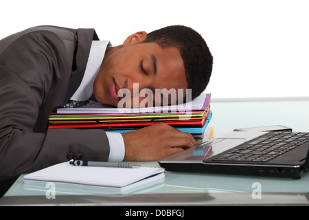 Businessman asleep on pile of folders Stock Photo