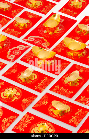 Chinese traditional currency gold yuanbao ingots and red pockets for Chinese New Year Stock Photo