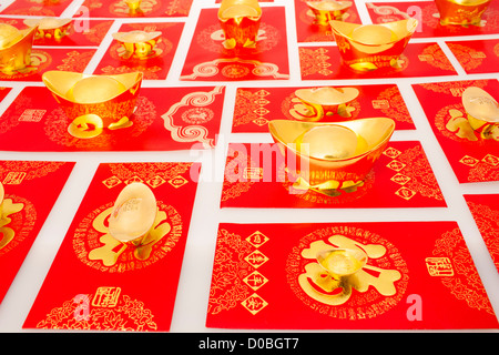 Chinese traditional currency gold yuanbao ingots and red pockets for Chinese New Year Stock Photo