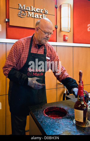 Man Preparing to Dip his Maker's Mark Bourbon Bottle in Wax at the Maker's Mark Distillery in Loretto, Kentucky Stock Photo
