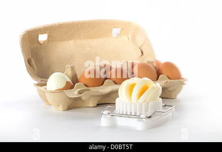 Egg slicer with a box of eggs with one half peeled egg Stock Photo