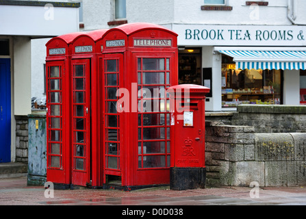 Traditional English red telephone boxes and postoffice pillar box on pavement in city street in England, UK Stock Photo