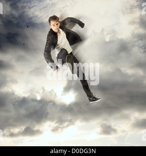 Cool young man jumping and kicking in the cloudy sky Stock Photo