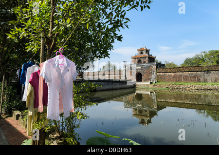 HUE, Vietnam — Local residents on the other side of the moat hang out their washing to dry at the Imperial City in Hue, Vietnam. A self-enclosed and fortified palace, the complex includes the Purple Forbidden City, which was the inner sanctum of the imperial household, as well as temples, courtyards, gardens, and other buildings. Much of the Imperial City was damaged or destroyed during the Vietnam War. It is now designated as a UNESCO World Heritage site. Stock Photo